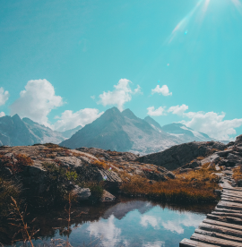 vertical-shot-wooden-passage-reflective-small-lake-mountain-range-horizon